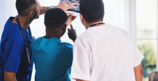 three person looking at x ray result